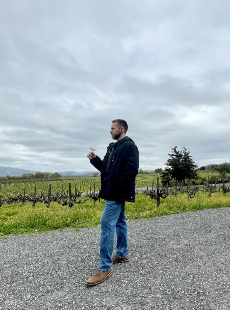 My husband drinking a glass of white wine in front of a Napa valley vineyard